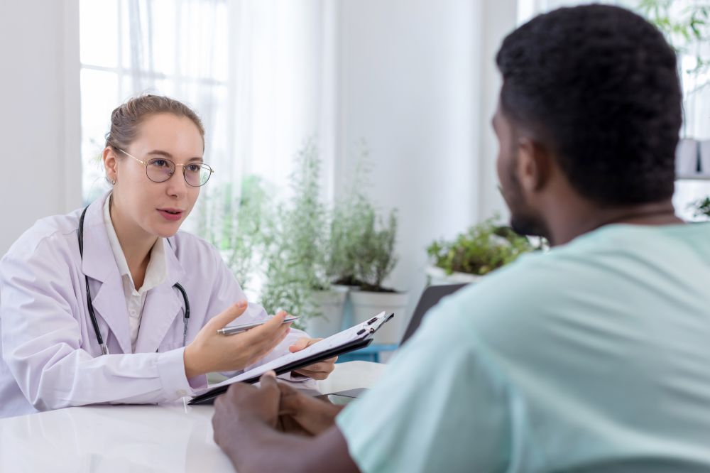 Doctor holding checklist and talking to man Patient at hospital.